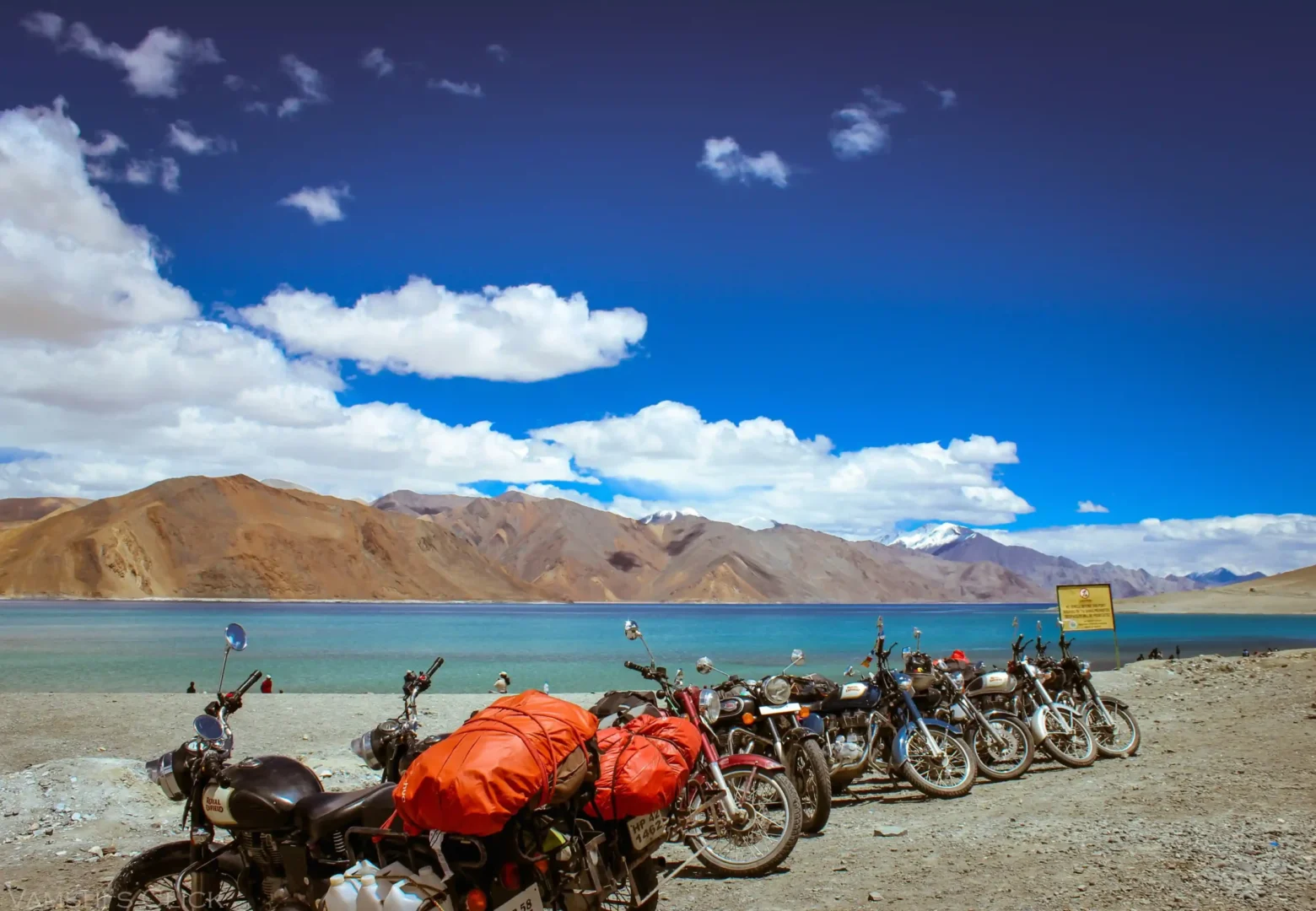 Motorbikes parked along the blue waters of Pangong Lake Ladakh